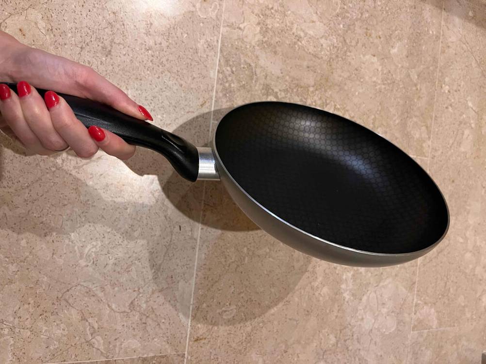 Seitenansicht einer Pfanne 24 cm im Test von einer Hand gehalten.