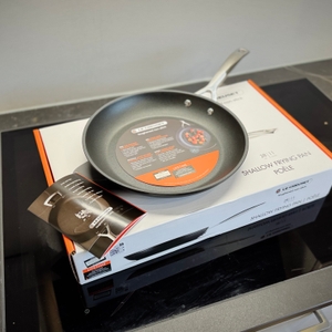 Die getestete Pfanne von Le Creuset steht zusammen mit der Gebrauchsanleitung auf der Verpackung.