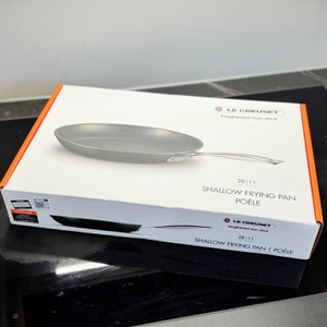 Die Verpackung der getesteten Pfanne von Le Creuset steht auf einem Kochfeld.