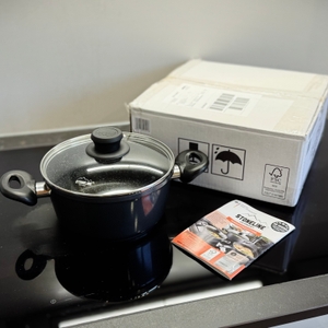 Der getestete Kochtopf von Stoneline steht zusammen mit der Verpackung auf einem Kochfeld.