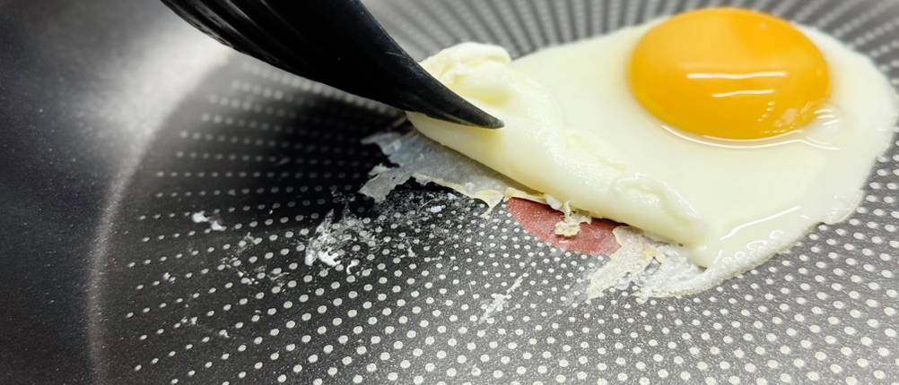 Pfannen-Test: Eine Person kratzt mit einem Pfannenwender anklebendes Ei aus der Tefal-Pfanne.