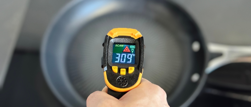 Eine Person misst mit einem Laser-Thermometer die Temperatur der getesteten Pfanne von Tefal.