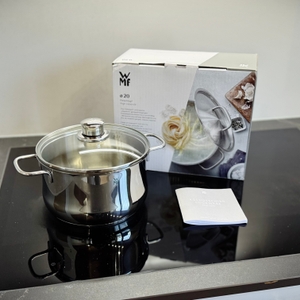 Der getestete Kochtopf von WMF steht zusammen mit der Verpackung auf einem Kochfeld.