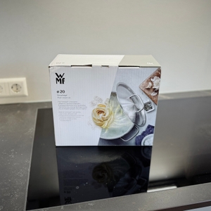 Die Verpackung des getesteten Kochtopfs von WMF steht auf einem Kochfeld.
