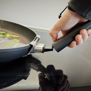 Eine Person nimmt den Stiel der getesteten Pfanne von Woll ab.