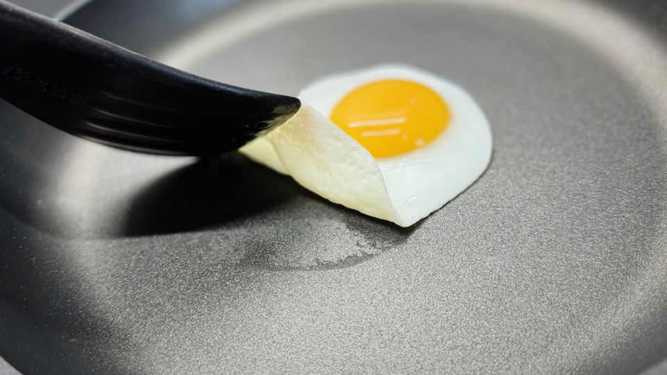 Eine Person hebt ein Spiegelei mit dem Pfannenwender in der getesteten Pfanne von Woll.