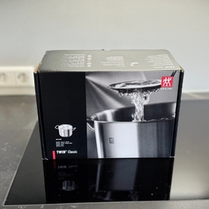 Die Verpackung des getesteten Kochtopfs von Zwilling steht auf einem Kochfeld.