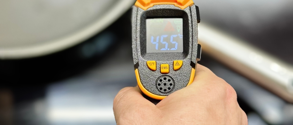 Pfannenset-Test: Eine Person misst mit einem Laser-Thermometer die Temperatur des Griffs einer Pfanne.