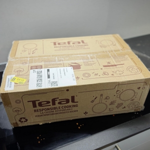Die Verpackung des getesteten Tefal-Pfannensets steht auf einem Kochfeld.
