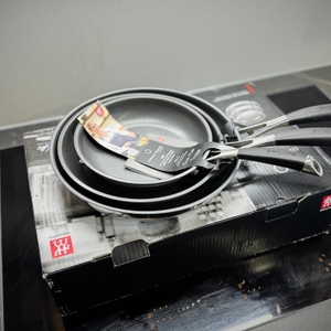 Die drei Pfannen des getesteten Pfannensets von Zwilling stehen auf der Verpackung.