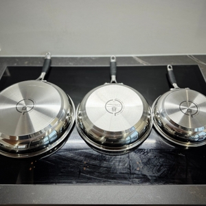 Pfannenset-Test: Die drei Pfannen des Zwlling-Sets liegen falsch herum auf einem Kochfeld.