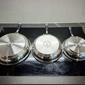 Pfannenset-Test: Die drei Pfannen des Zwlling-Sets liegen falsch herum auf einem Kochfeld.