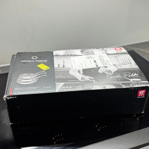 Die Verpackung des getesteten Zwilling-Pfannensets steht auf einem Kochfeld.