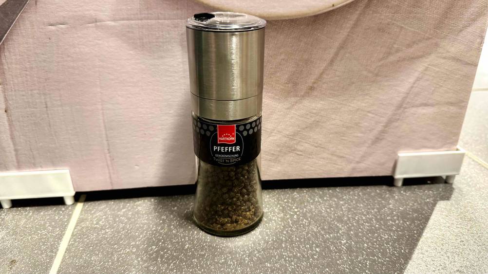 Eine Mühle Pfeffer im Test vor einer hellen Fläche stehend.