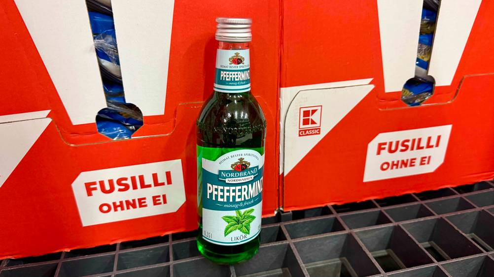 Vor roten Kartons steht eine Flasche des Pfefferminzlikörs im Test.