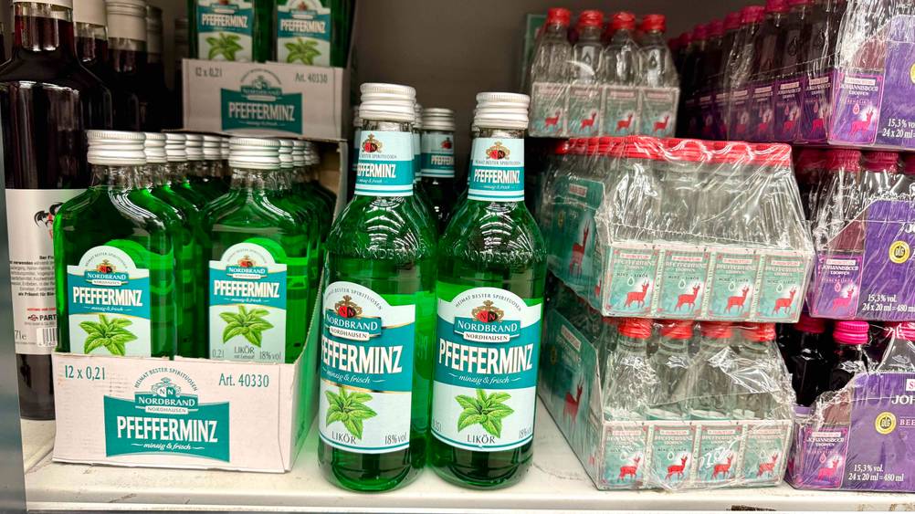 Mehrere Flaschen Pfefferminzlikör im Test neben anderen Produkten in einem Verkaufsregal.