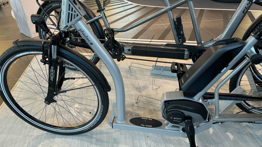 E-Bike-Dreirad im Test: Detailansicht von der Seite auf ein batteriebetriebenes Modell im Ausstellungsbereich eines Geschäfts.