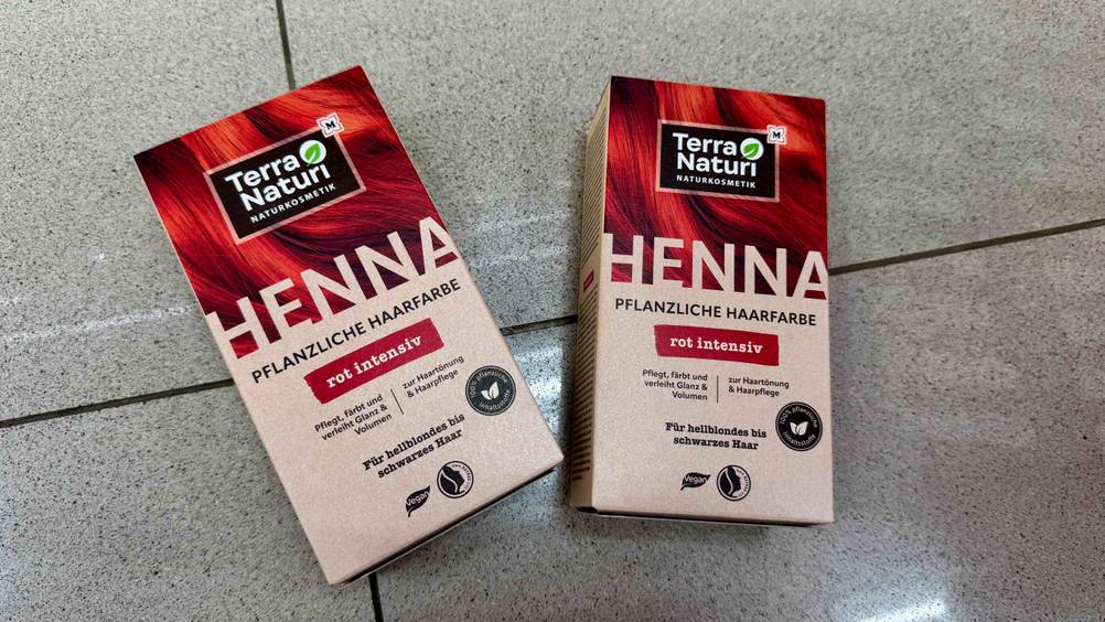 Pflanzenhaarfarbe-Test: Zwei Packungen nebeneinander von oben auf einer Fließenfläche liegend.