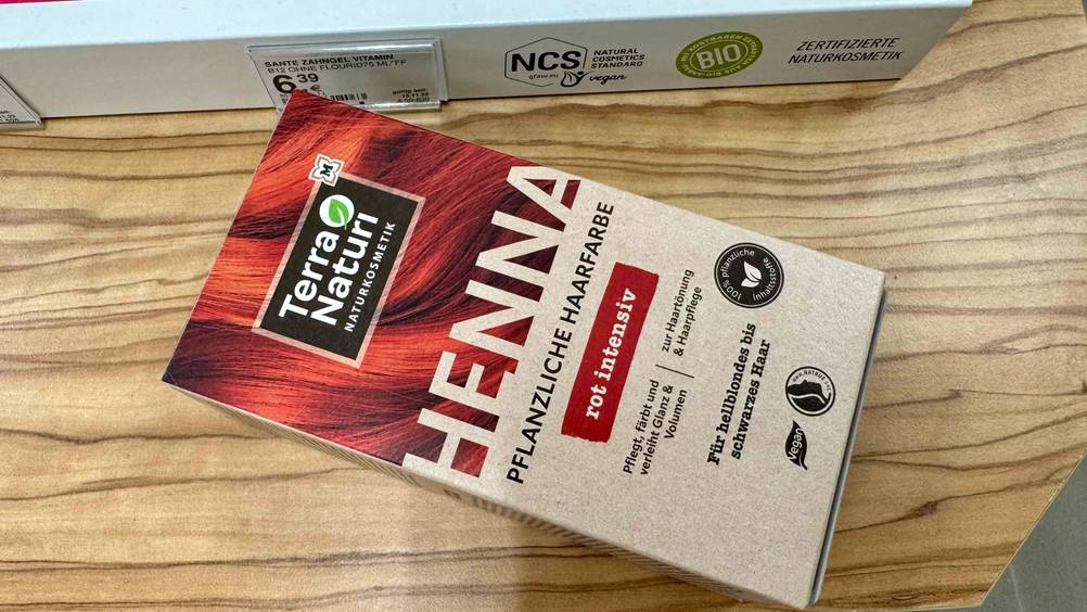 Eine Packung der getesteten Pflanzenhaarfarbe horizontal auf einer Holzfläche.