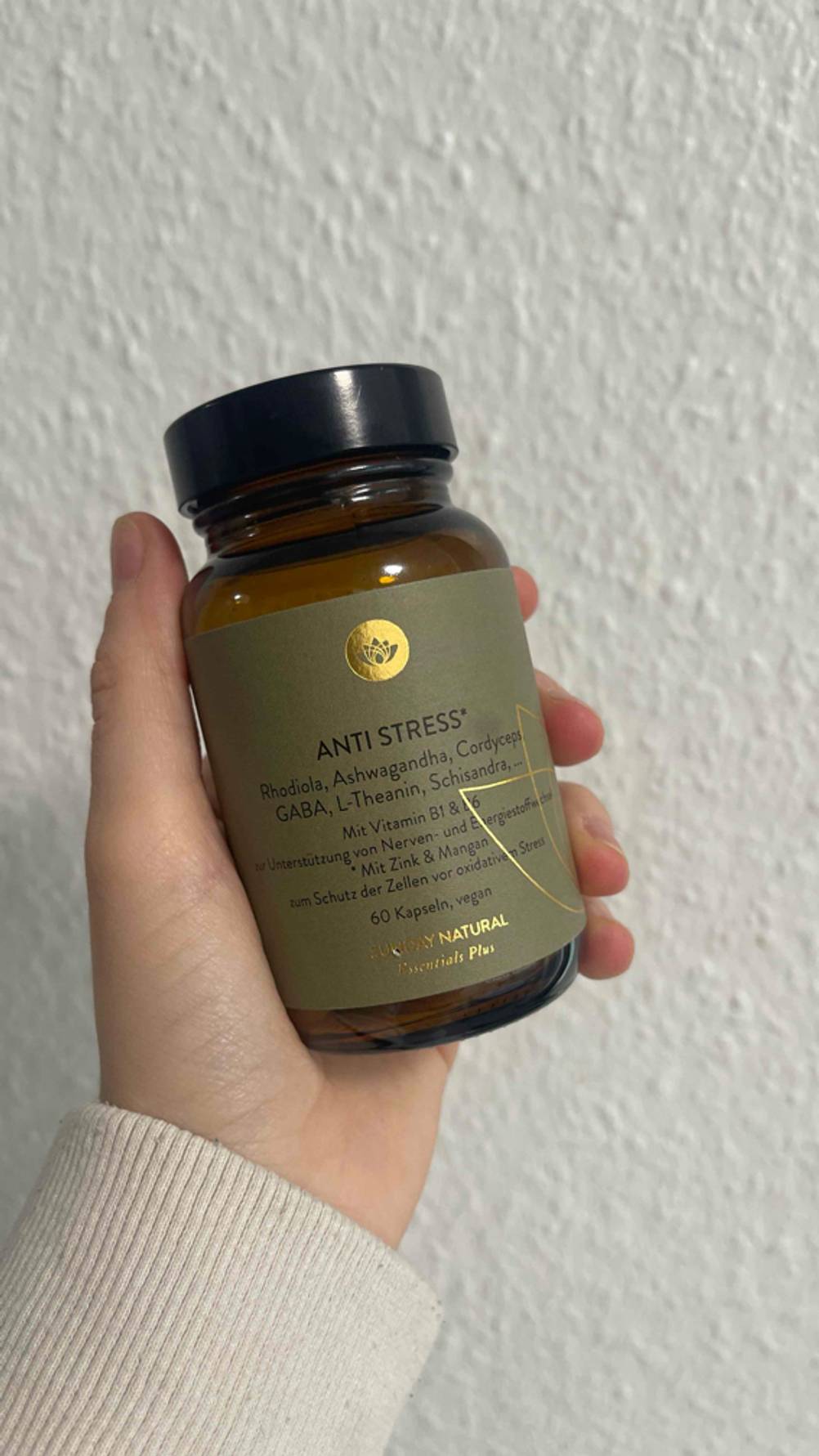 Eine Hand hält eine blickdichte Dose mit olivefarbenem Etikett, die das getestete pflanzliche Beruhigungsmittel enthält, vor einer weißen Wand.