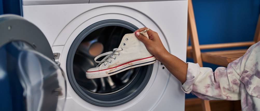 Energiesparende-Waschmaschine-Test: frau-packt-sneaker-in-die-waschmaschine
