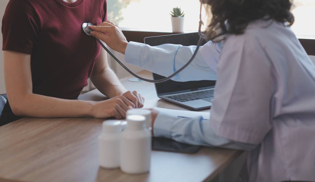 Eine Ärztin hört den Brustkorb eines Patienten ab.