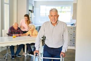Zufriedener Senior mit Gehhilfe in einem Altenpflegeheim.