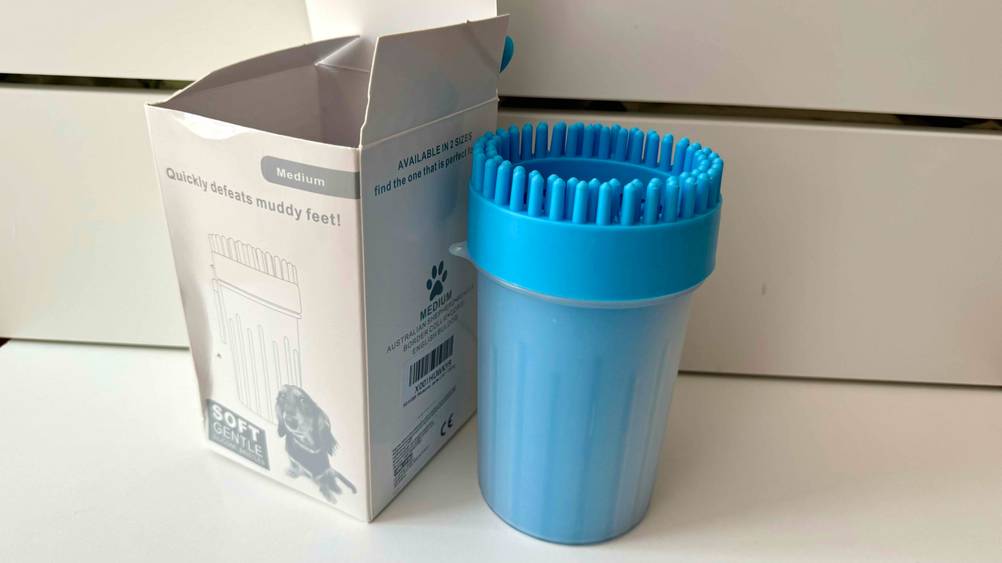 Ein Pfotenreiniger im Test steht neben seiner Verpackung auf einer hellen Fläche.