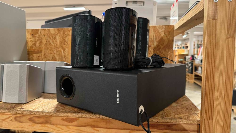 Im Test: Ein 5-1-Soundsystem steht mit Gerät und den darauf stehenden runden Lautsprechern in einem Holzregal.