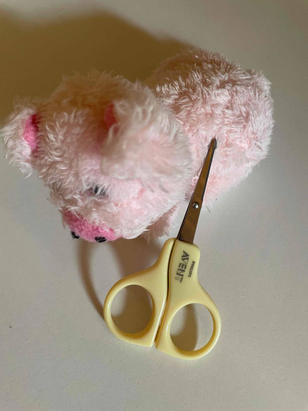 Baby-Nagelscheren-Test: Die Schere liegt auf einem kleinen rosafarbenen Plüschtier.