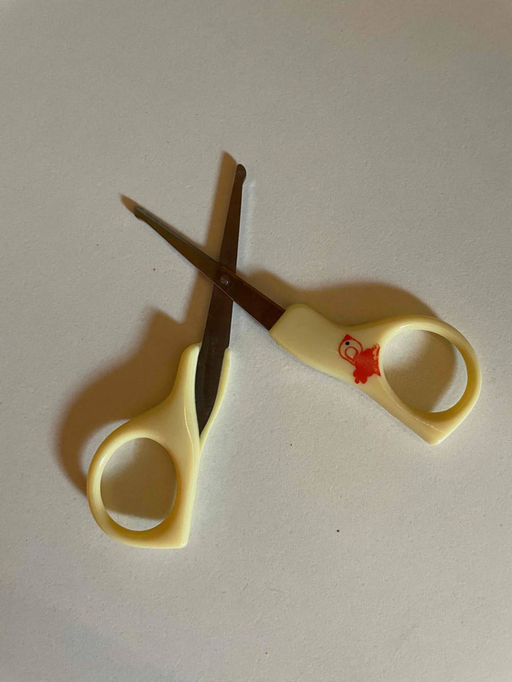 Baby-Nagelschere getestet: Eine geöffnete, gelbe Schere auf einer hellen Oberfläche.