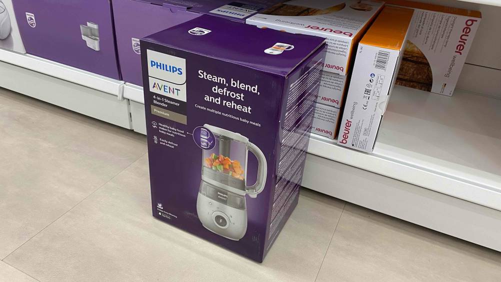 Im Test: Ein Originalkarton des Babynahrungszubereiters von vorne vor einem Regal.