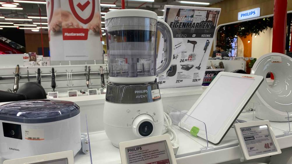 Auf einem Verkaufsregal steht neben anderen Produkten ein getesteter Babynahrungszubereiter.