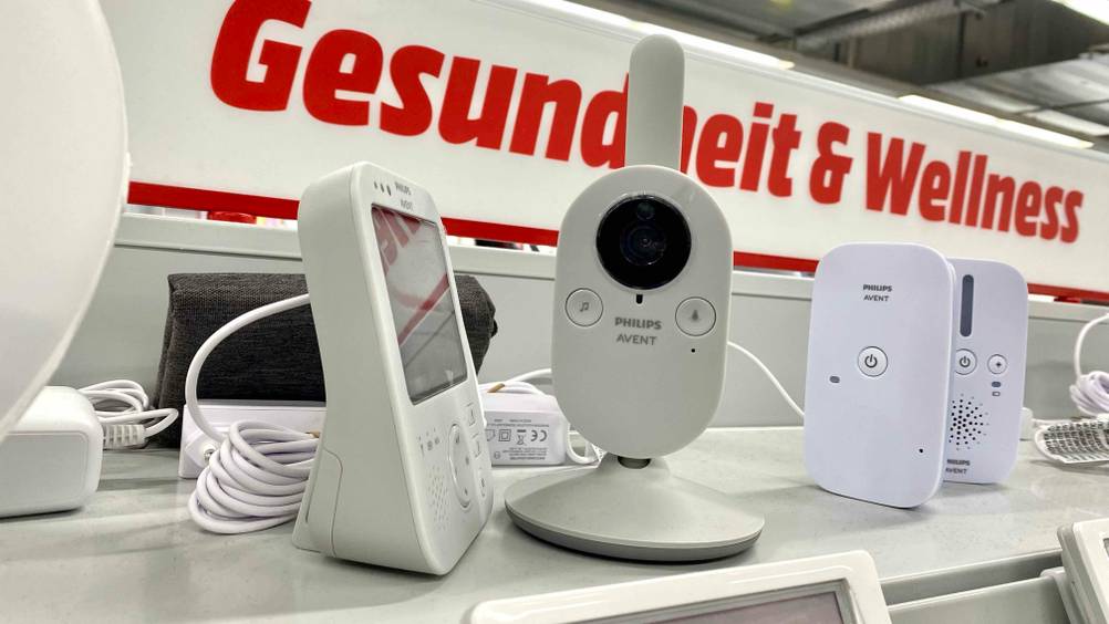 Ein Babyphone im Test von der Seite in einem Verkaufsregal im Hintergrund andere Geräte.