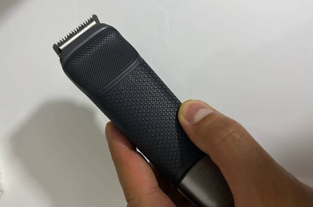 Ein anthrazitfarbener Haarschneider im Test in einer Hand vor weißem Hintergrund; der Fokus liegt auf der Metall-Klinge.