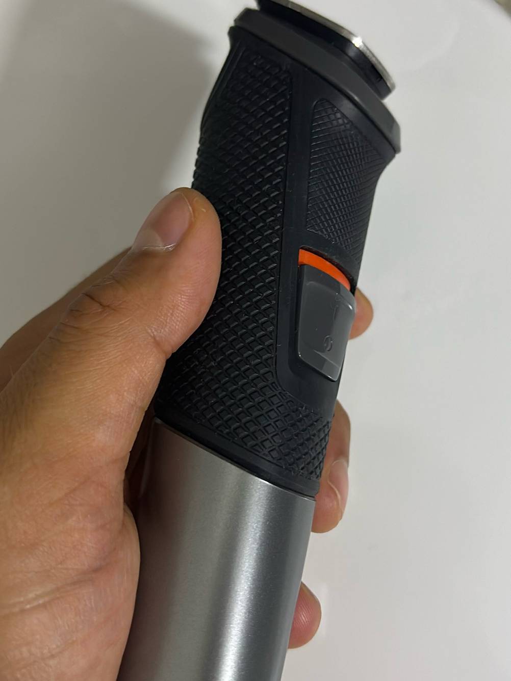 Ein anthrazitfarbener getesteter Haarschneider befindet sich in einer Hand, der Fokus liegt auf der rutschfesten Grifffläche und der Einschalttaste.