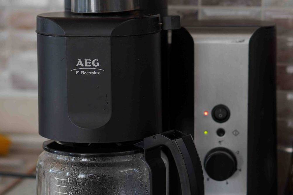 Kaffeemaschine mit Mahlwerk im Test: Das Modell von AEG steht auf einer Arbeitsfläche. Im Vordergrund stehen zwei weiße Tassen mit Kaffee.