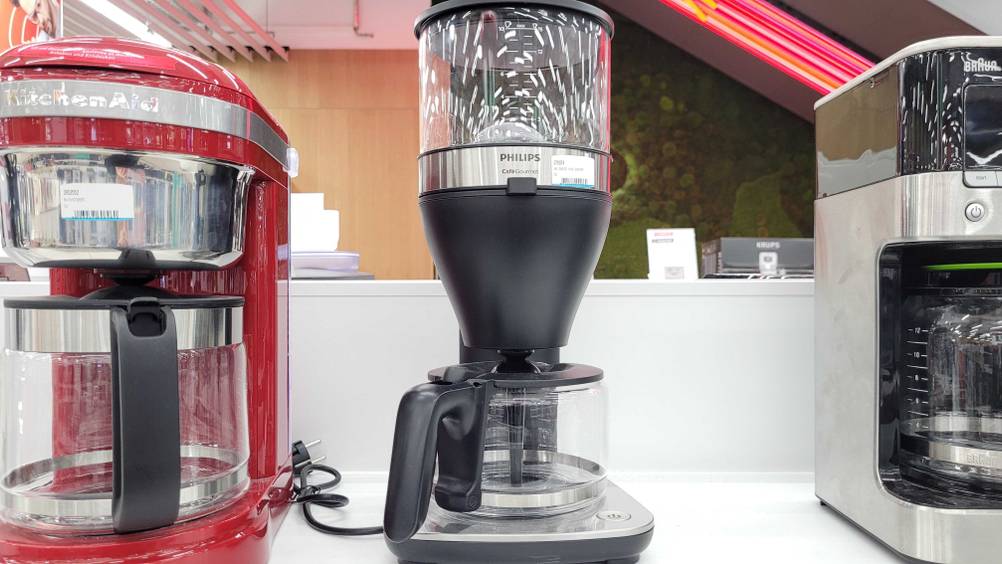 Eine getestete Philips-Kaffeemaschine zwischen anderen Geräten auf einem Verkaufsregal.