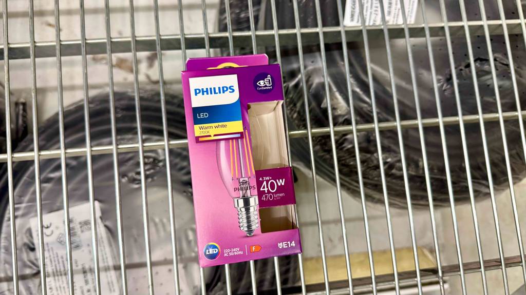 Ein pinke Verpackung mit einer getesteten LED-Lampe E14 liegt auf einem Gitter.