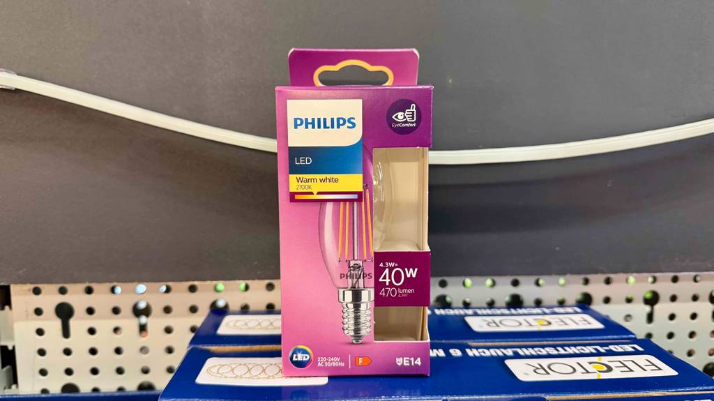 Ein pinke Verpackung mit einer getesteten LED-Lampe E14 steht auf einer blauen Verpackung inklusive Lichtschalter.