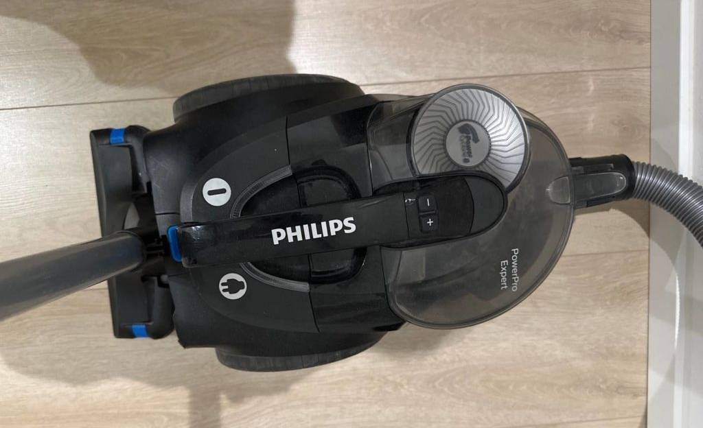 Draufsicht Tierhaarstaubsauger im Test: ein schwarzes Modell der Marke Philips steht mit rückwärtig eingehängtem Teleskopstiel auf einem hellen Holzboden.