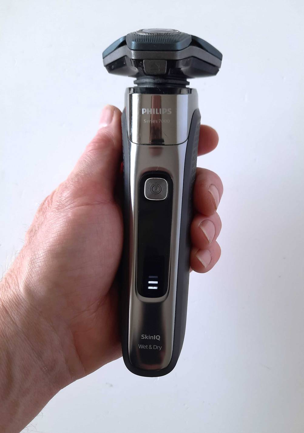 Philips-Rasierer-Test: Eine Hand hält einen Rasierer vor eine helle Wand.