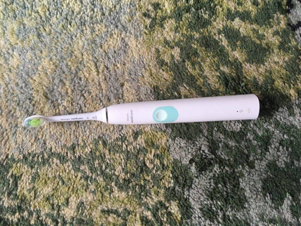 Weiße Philips Sonicare Schallzahnbürste im Test liegt auf einem gemusterten Teppich.