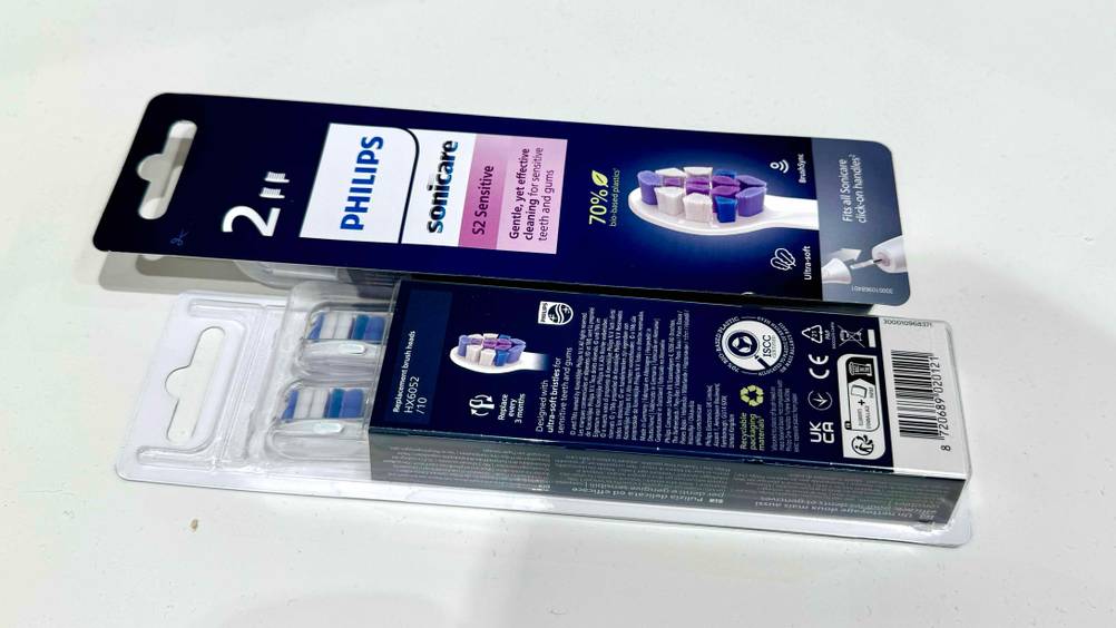 Philips-Sonicare-Ersatzbürsten getestet: Zwei Packungen liegen auf einer hellen Fläche, einmal Vorderseite nach oben, einmal Rückseitel.