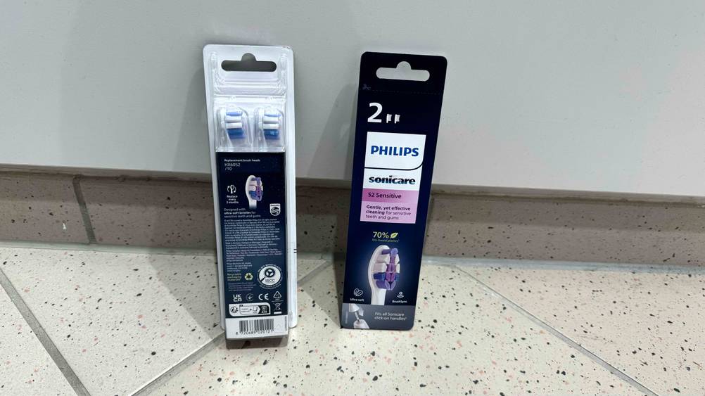 Zwei Packungen der getesteten Philips-Sonicare-Ersatzbürsten, eine von vorne eine von hinten lehnen an einer Wand.
