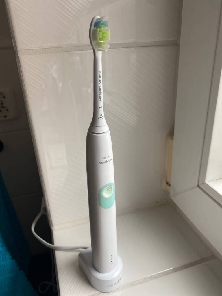 Weiße Sonicare Schallzahnbürste im Test steht auf ihrer Ladestation auf einer weiß gefliesten Fensterbank.