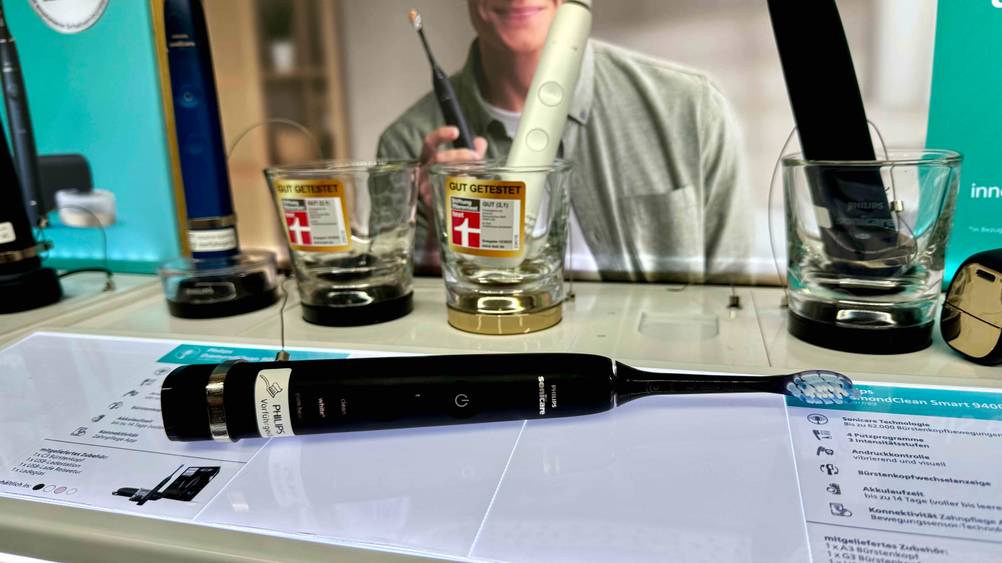 Die getestete Philips-Sonicare-Zahnbürste liegt vor mehreren anderen Produkten auf einer Informationsfläche.