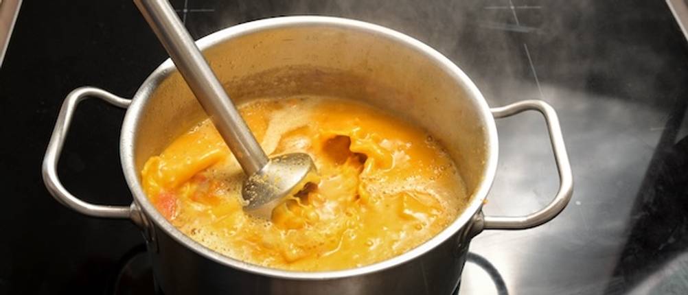 Philips-Stabmixer mit Suppe getestet: Ein Mixstab aus Edelstahl befindet sich in einem Topf mit Kürbissuppe.