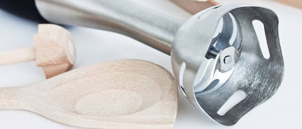 Philips-Stabmixer getestet: Eine Großaufnahme von der Mixglocke eines Mixstabes, daneben liegt ein heller Holzkochlöffel.