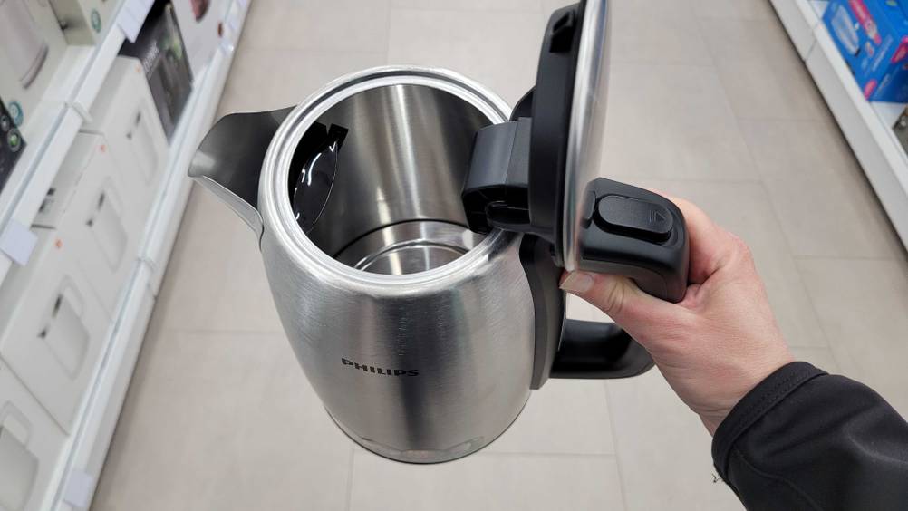 Eine Hand hält einen geöffneten Philips-Wasserkocher hoch.